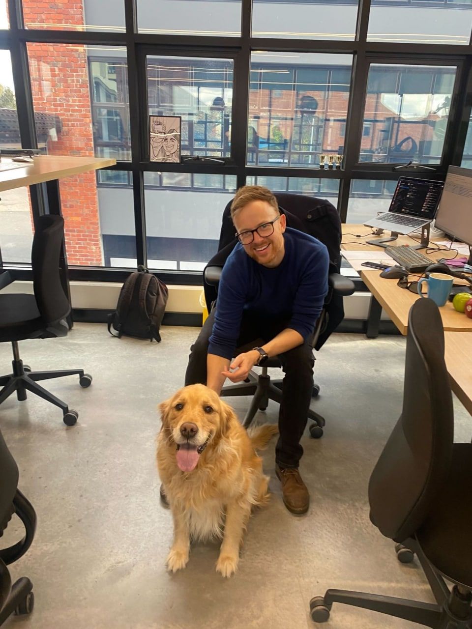 Jim Ferguson at his desk with a golden retriever sitting beside him